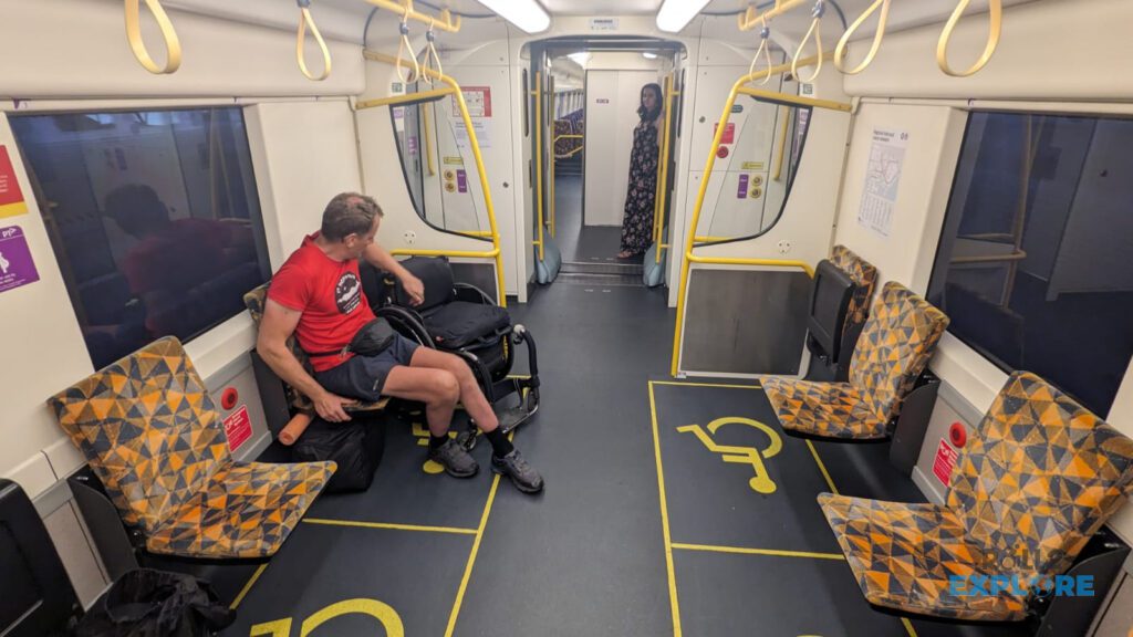 Nick in a wheelchair on V/Line train in  special designted area next to the door. He is transfering from the wheelchair onto the seat.