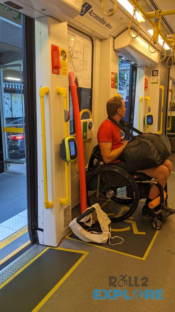 Nick in a wheelchair inside the tram in a special designated area. The doors of the tram are opened and you can see that it's the same level like the platform. 